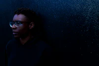 a man in a black hoodie leaning against a wall