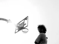 a black and white photo of a man standing in front of a basketball hoop