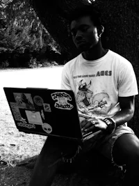 a man sitting under a tree with a laptop