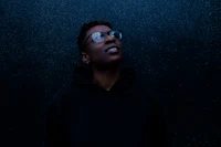 a black man wearing glasses and a black hoodie