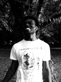 a black and white photo of a man smiling in front of a tree