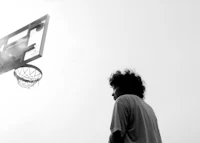 a black and white photo of a man standing in front of a basketball hoop