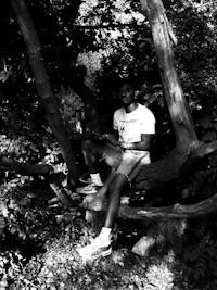 black and white photo of a man sitting in a tree