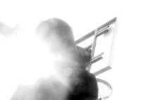 a black and white photo of a person standing in front of a basketball hoop